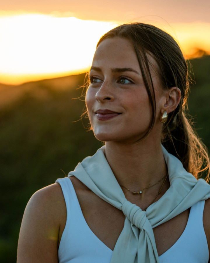 A woman standing on a hillside at sunset